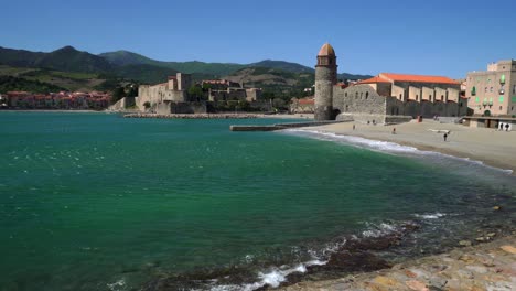 Waves-surge-up-and-down-the-beach-during-high-winds-in-Collioure-with-the-historic-town-in-the-background