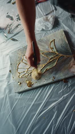 applying gold leaf to a floral painting