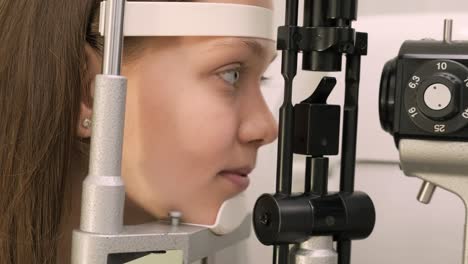 oftalmólogo chequea la vista de un adolescente con equipos modernos. médico chequeando los ojos con un dispositivo de biomicroscopio. toma de dolly de una doctora examinando la estructura del ojo con la ayuda de equipos médicos