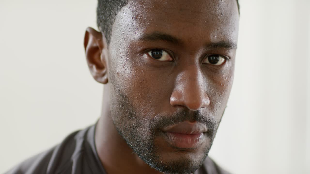 Stanza luminosa in cui un uomo afroamericano di mezza età ammicca e contrae la mascella rimanendo concentrato