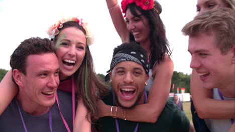 young friends piggy backing at a music festival, close-up