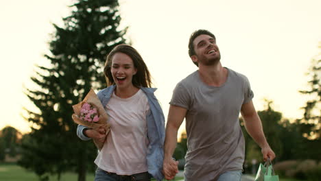 Happy-couple-with-flowers-running-in-summer-park.-Couple-in-love