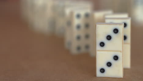 close up view of row of white dominoes being toppled from the back to the front in slow motion