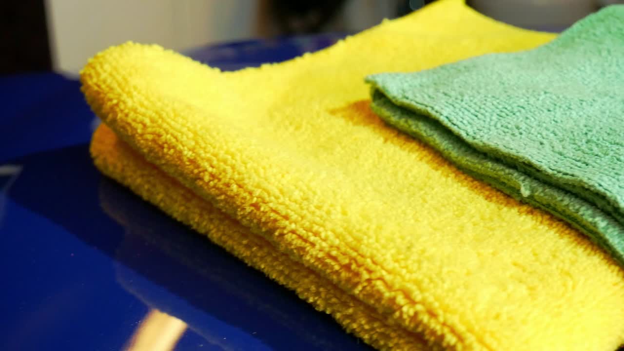 Left to right sliding shot of various microfiber towels in yellow, green and blue