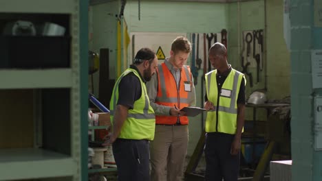 two caucasian and an african american male factory worker in discussion