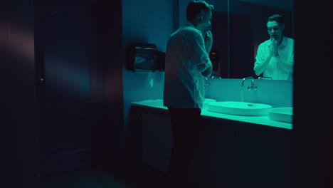 man washing hands in a dark bathroom