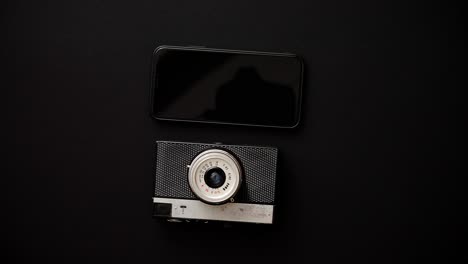 Old-retro-film-camera-and-modern-smartphone-on-black-background