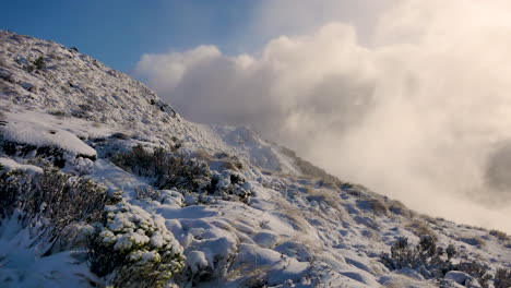 panning shot of lighting cloudscape hiding behind snowy mountain during kepler track hike in new zealand