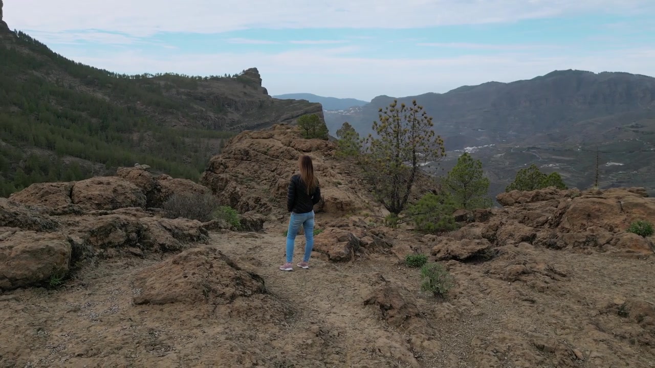 Donna in piedi su una cima di montagna, che ammira la vista panoramica del paesaggio vulcanico, inclusa Roque Nublo a Gran Canaria