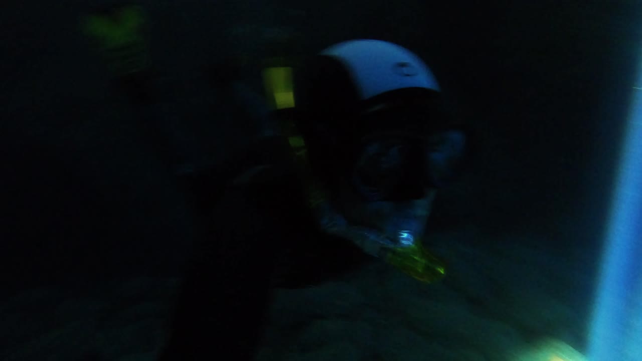 Mysterious underwater scenery of a scuba diver exploring a sea cave and passing by a natural beam of sun light illuminating the dark waters, Vis island, Adriatic Sea, Croatia