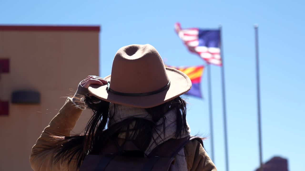 Persona con sombrero y mochila con banderas de Estados Unidos y Arizona