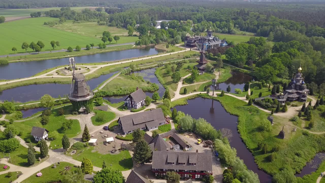 Aerial view of the Mühlenmuseum Gifhorn, showcasing historic windmills surrounded by lush greenery and water features in a picturesque setting.