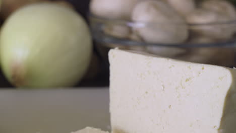slicing tofu with a knife on a cutting board. - close up shot