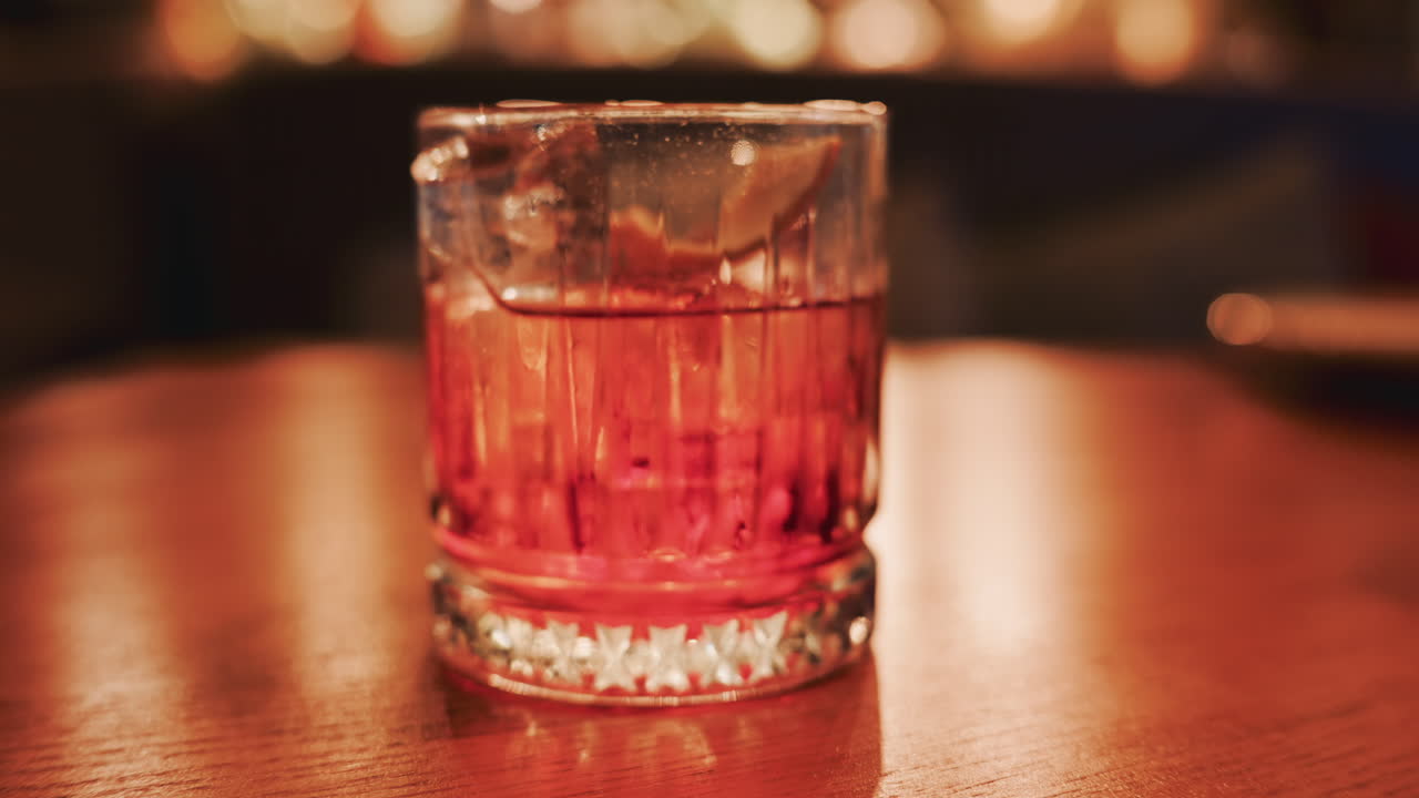 Close up of a cocktail served on a wooden table in a warmly lit restaurant