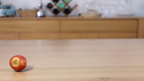 an apple rolls and stops on a wooden counter