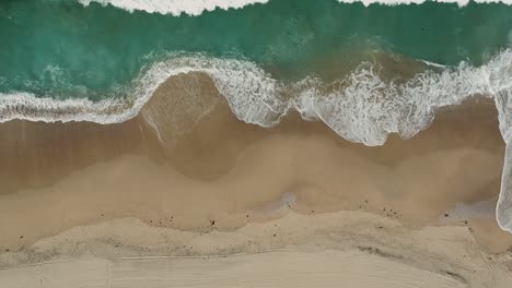 la cámara de la tarde baja la vista del dron desde el agua y las pequeñas olas de la playa redonda, california
