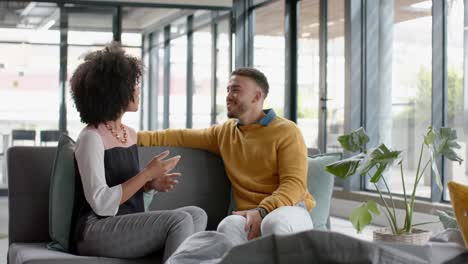 diverse man and woman discussing with each other sitting on the couch at office