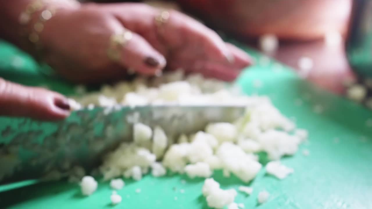 Female hand chopping Cauliflower on a green cutting board with a kitchen knife in a Mexican health food restaurant