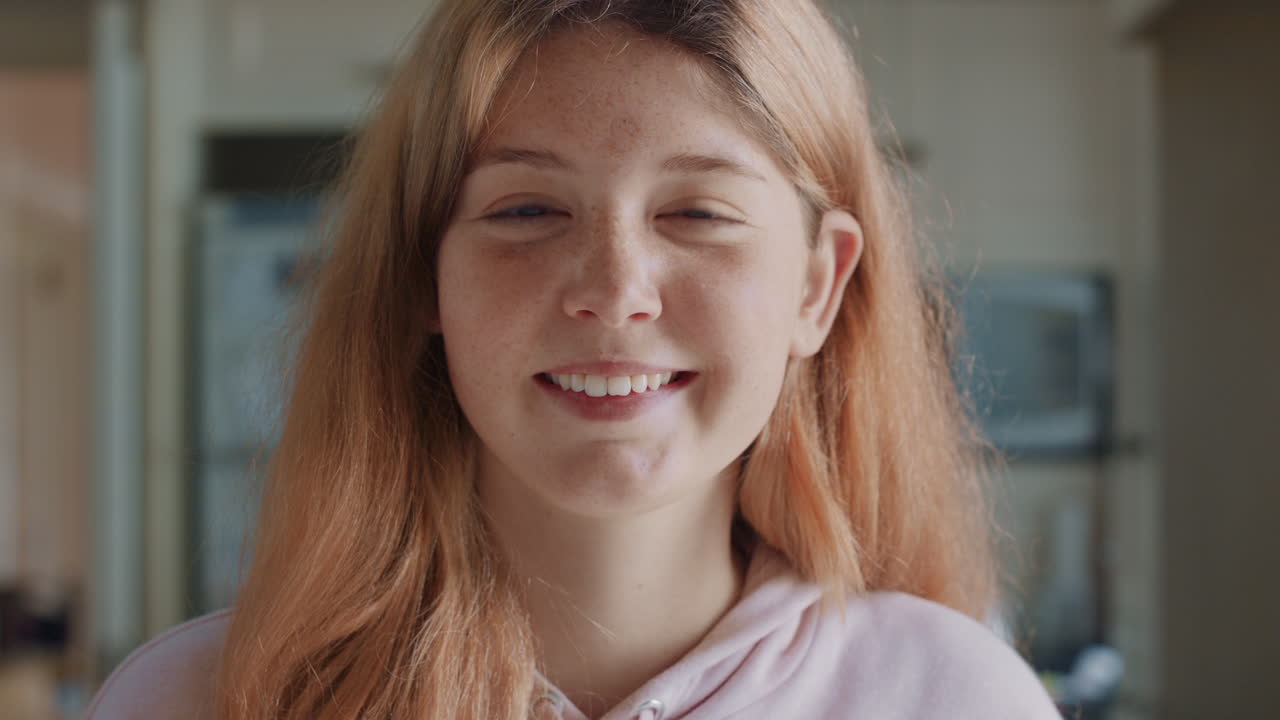 retrato de una hermosa adolescente pelirroja con pecas en la cocina en casa sonriendo feliz disfrutando de un estilo de vida despreocupado