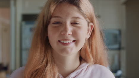 portrait beautiful red head teenage girl with freckles in kitchen at home smiling happy enjoying carefree lifestyle