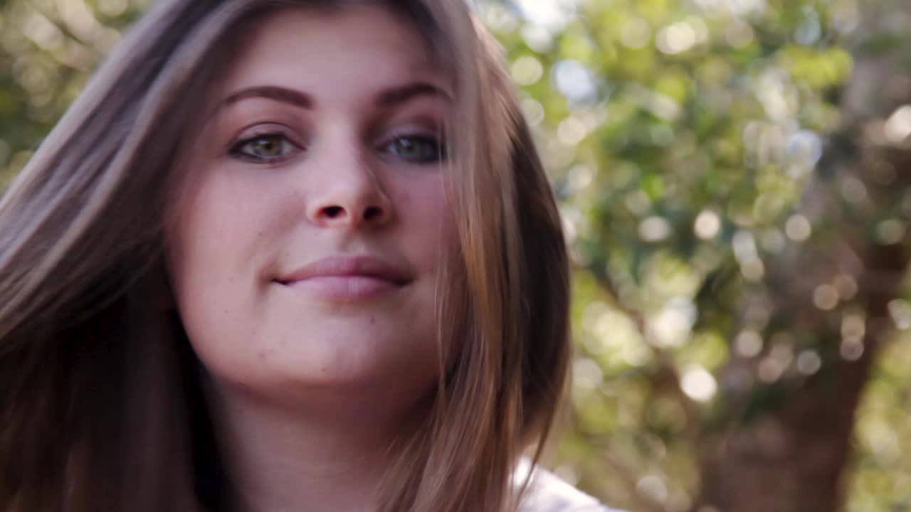 mujer morena levanta la cabeza en el marco y sonríe y mueve el pelo en un día ventoso