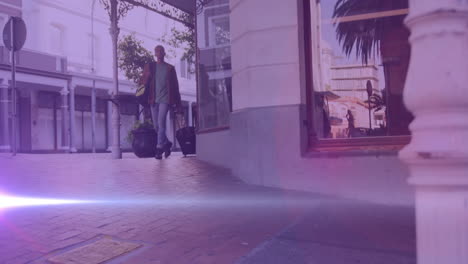 video of coloured lights over biracial man walking to work, wheeling suitcase in street