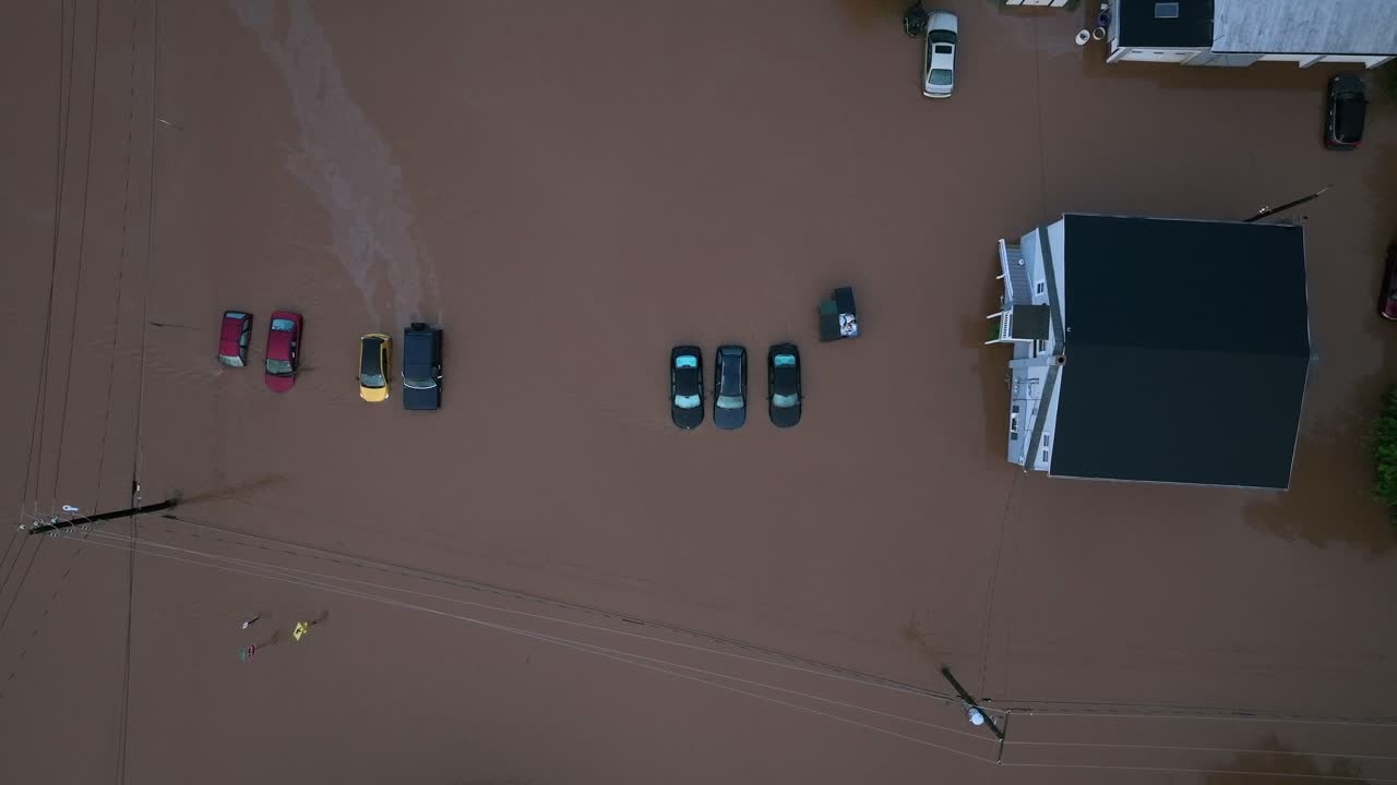Oversvømmede biler efter en kraftig tropisk storm i Amerika. Luftfoto, der stiger opad, set oppefra. Skumringsstemning. Parkeringsområde oversvømmet med beskidt vand. Ødelagte biler.