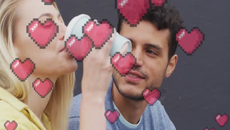 animation of heart icons floating over happy caucasian couple talking and drinking takeaway coffee