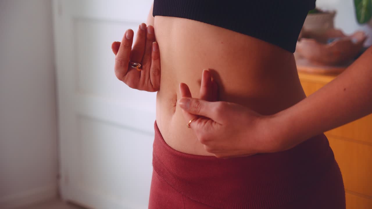 cerrar las manos de una mujer caucásica masajeando su propio estómago