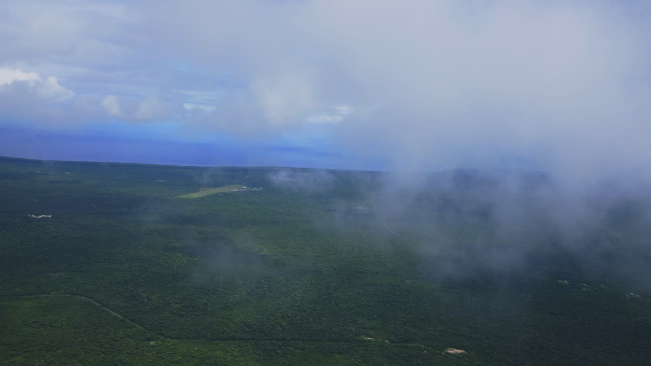 una vista desde un avión captura la impresionante vista de volar a través de las nubes sobre una isla de bosque tropical, mostrando la belleza de las nubes esponjosas que contrastan con la vegetación verde