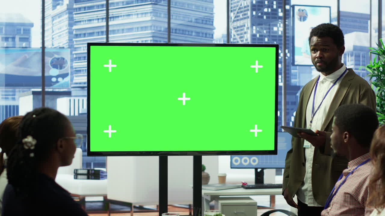 un equipo de trabajo diverso discute las estrategias corporativas con una gran pantalla verde