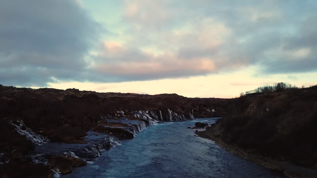 drone con movimientos cinematográficos muestra una hermosa cascada islandesa, hraunfossar, a la luz del atardecer desde múltiples ángulos