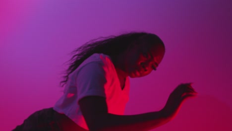 studio shot of young woman dancer dancing against blue and pink lit background 3