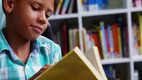 niño discapacitado leyendo un libro en la biblioteca de la escuela