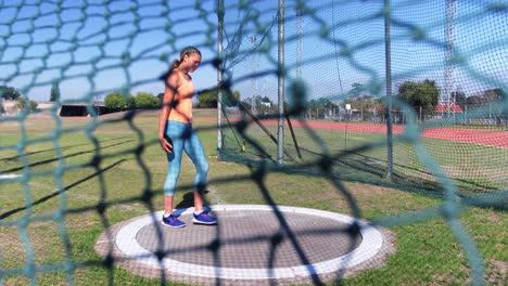 vista frontal de una atleta caucásica preparándose para el lanzamiento de disco 4k