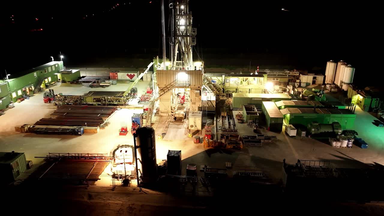 vista nocturna de la estación de perforación de gas con luces iluminadas - toma aérea de un dron
