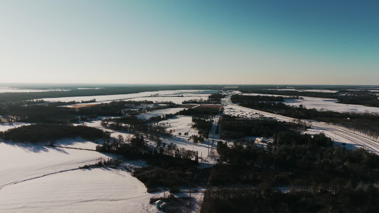 Drone footage of a tranquil South Georgia landscape with snow-covered fields and scattered trees. Captured with a slow push-in movement during a rare snowfall.