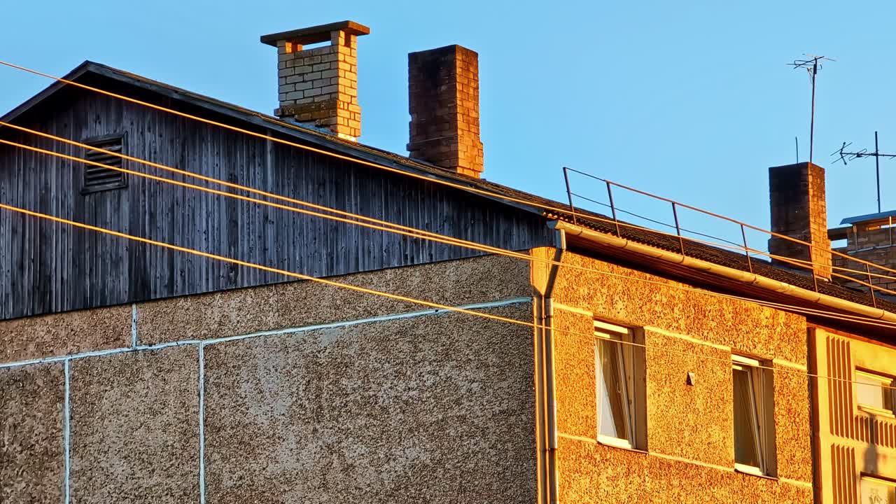 Brick Chimneys and Antennas on Old Residential Building Rooftop at Golden Hour