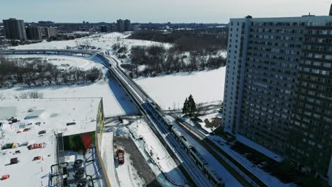 Drone-shot-train-travelling-through-Ottawa-city-in-Canada-in-winter-snow
