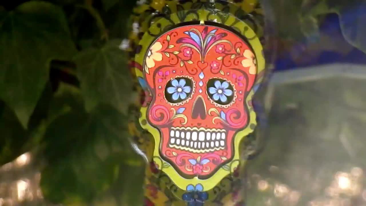 cráneo de azúcar de metal hipnótico adorno de jardín giratorio colorido decorativo colgando del árbol primer plano