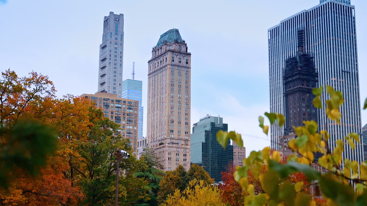 Belos arranha-céus de Nova York e árvores coloridas abaixo deles. Filmagem do Central Park na temporada de outono