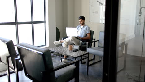 working in office, man using laptop while sitting in modern meeting room
