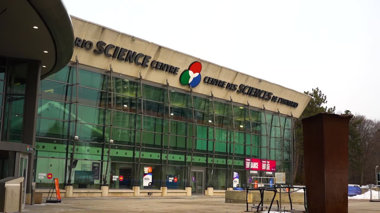 Gimbal shot panning up to reveal the front of the Ontario Science Centre in spring with snow on the ground