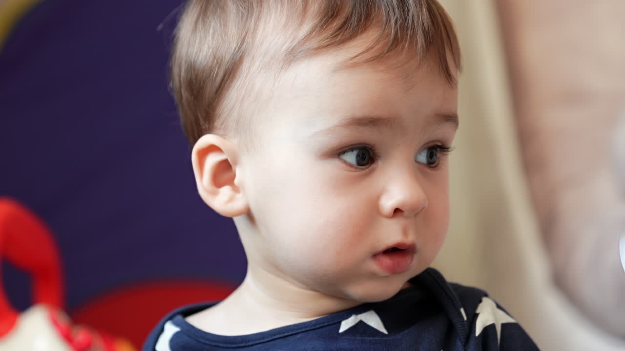 Pretty toddler boy in blue shirt. Lovely child close up portrait. Cute kid looking to the sides.