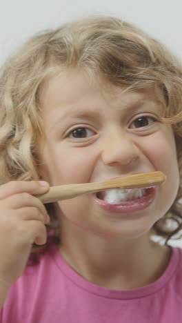 una niña pequeña cepillándose los dientes en vertical