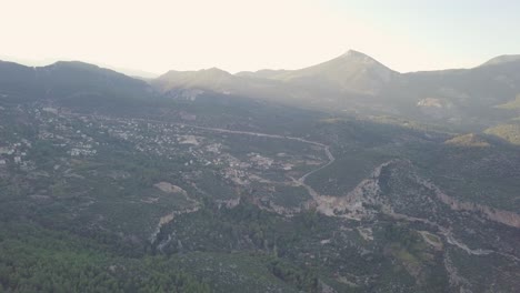 La-Luz-Del-Sol-Se-Filtra-A-Través-Del-Paisaje-Montañoso-Del-Pequeño-Pueblo-De-Geyikbayiri-En-Antalya,-Turquía,-Como-Se-Muestra-En-Un-Clip-Aéreo-De-Movimiento-Lento-Tomado-Por-Un-Dron