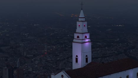 Drone-shot-of-Monserrate-church-overlooking-the-city-of-Bogota,-Colombia-at-blue-hour