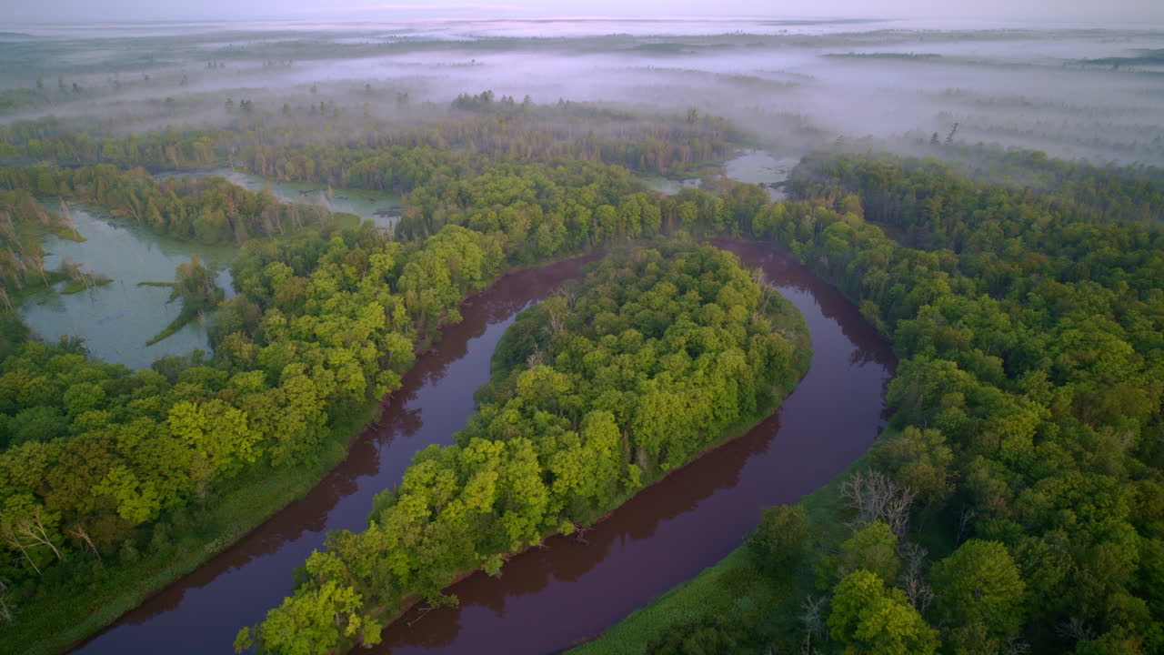 Dramatic drone shot showing foggy manistee river in the morning