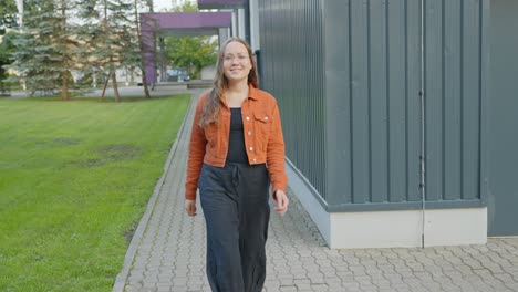 woman confidently walks along the sidewalk toward the camera, static closeup