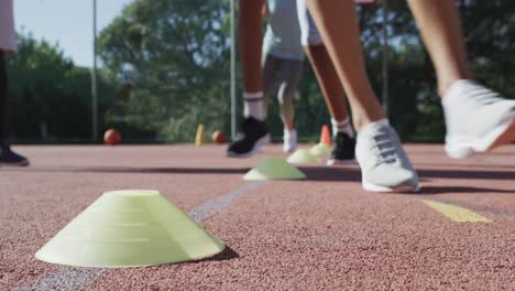 happy diverse female basketball team training with male coach on sunny court, in slow motion